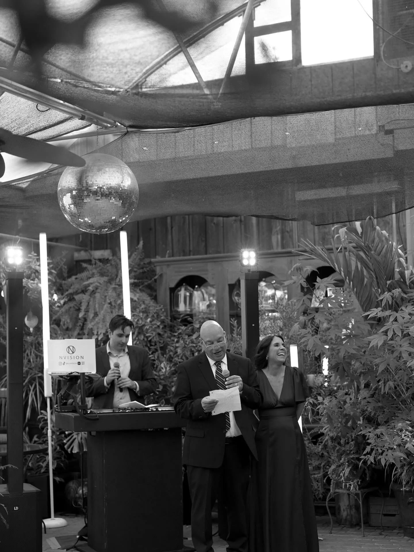 NVision DJ and MC leading toasts under a disco ball at a wedding reception