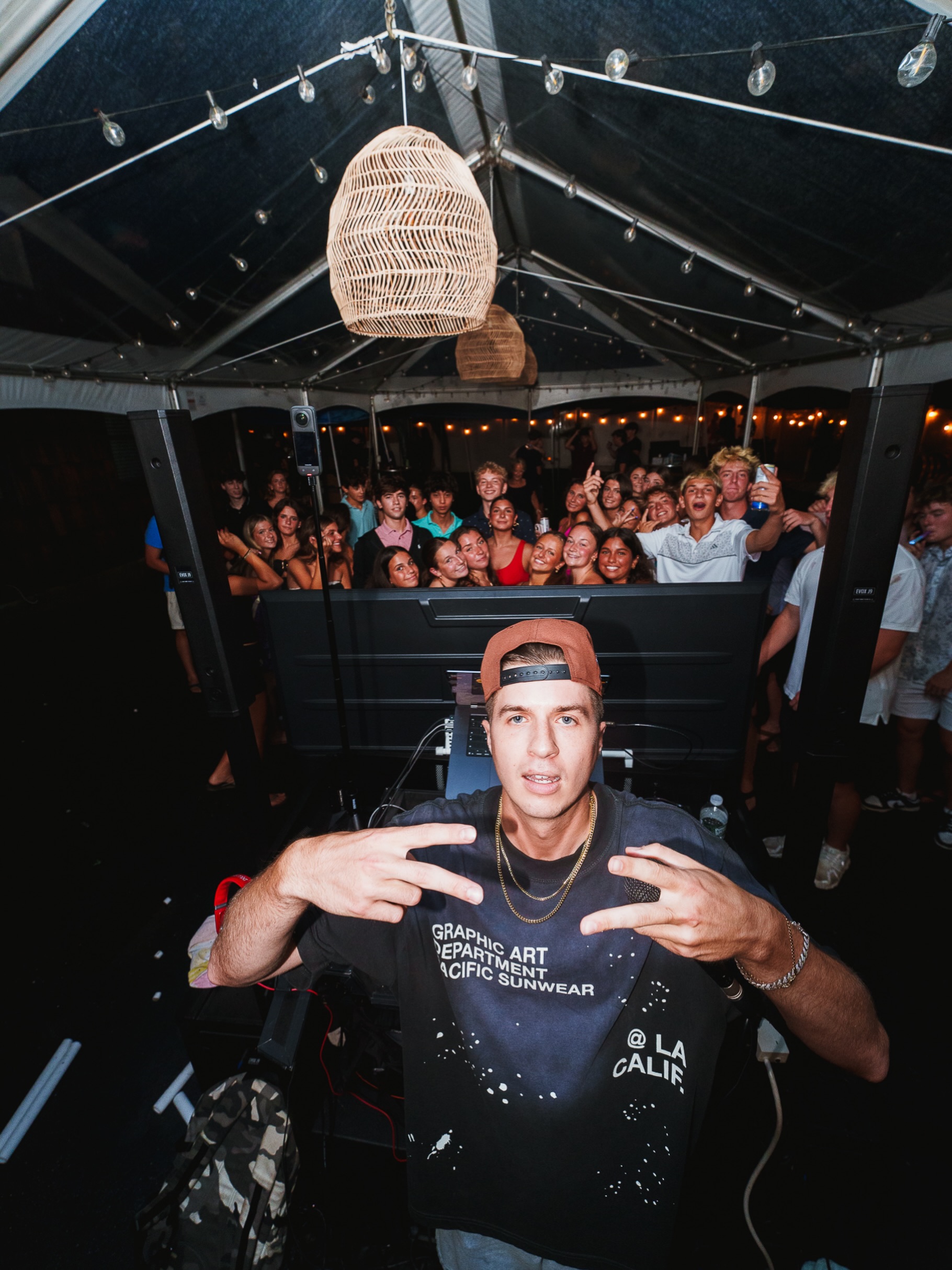 DJ Chris G posing at the DJ booth in front of a packed tent party crowd