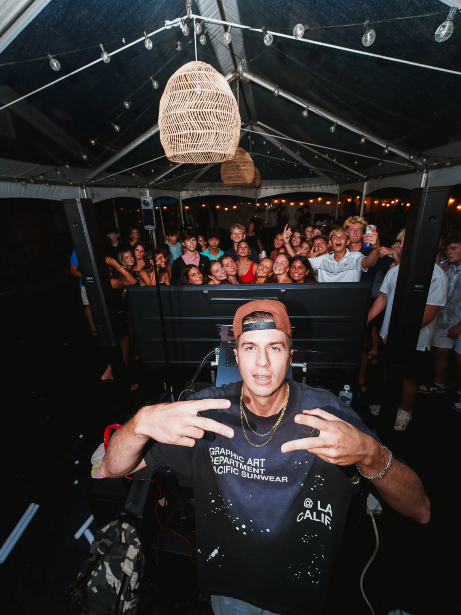 DJ Chris G posing at the DJ booth in front of a packed tent party crowd