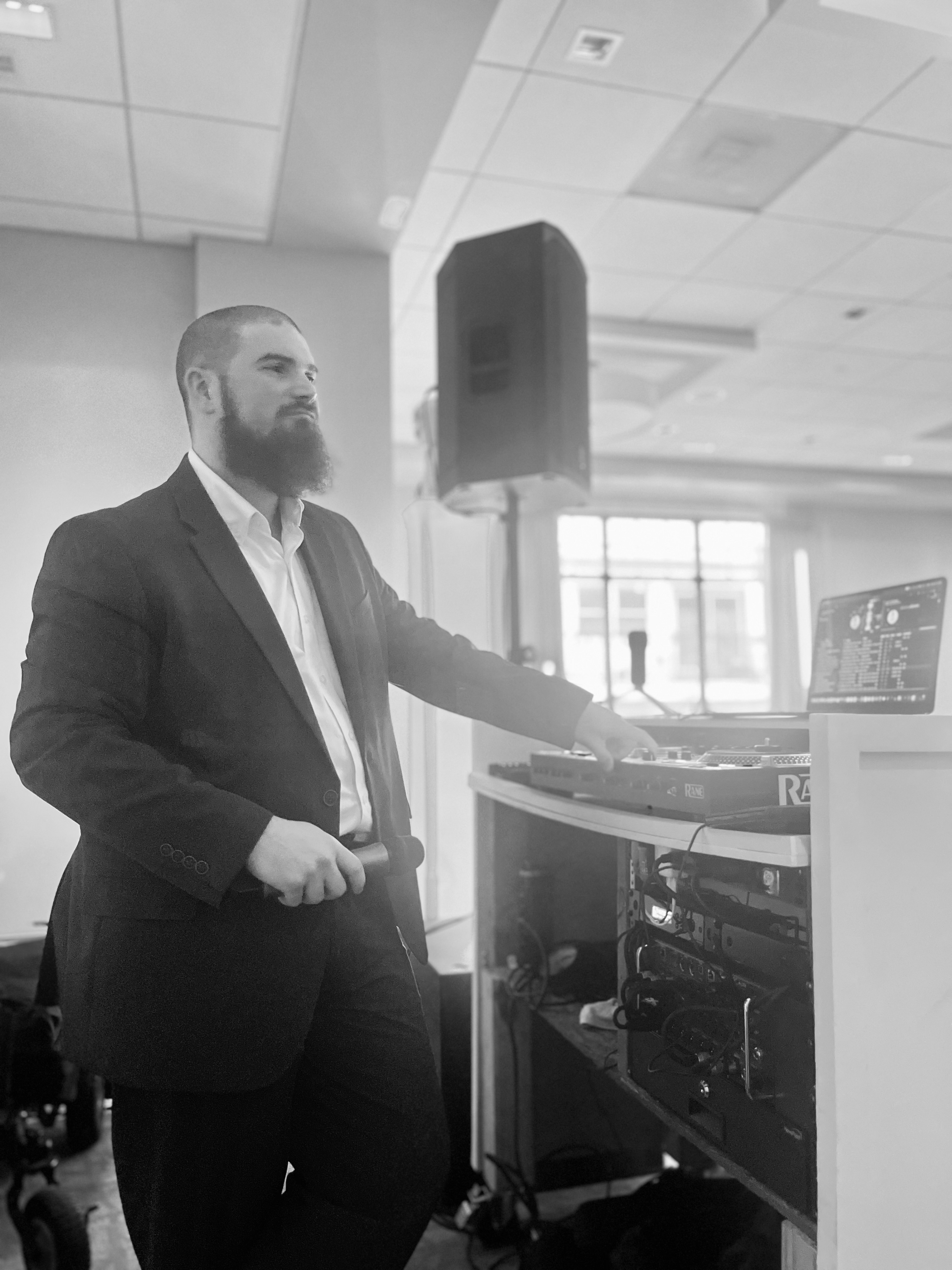 Marshall VanBuren MCing with a microphone at the DJ booth during a wedding reception