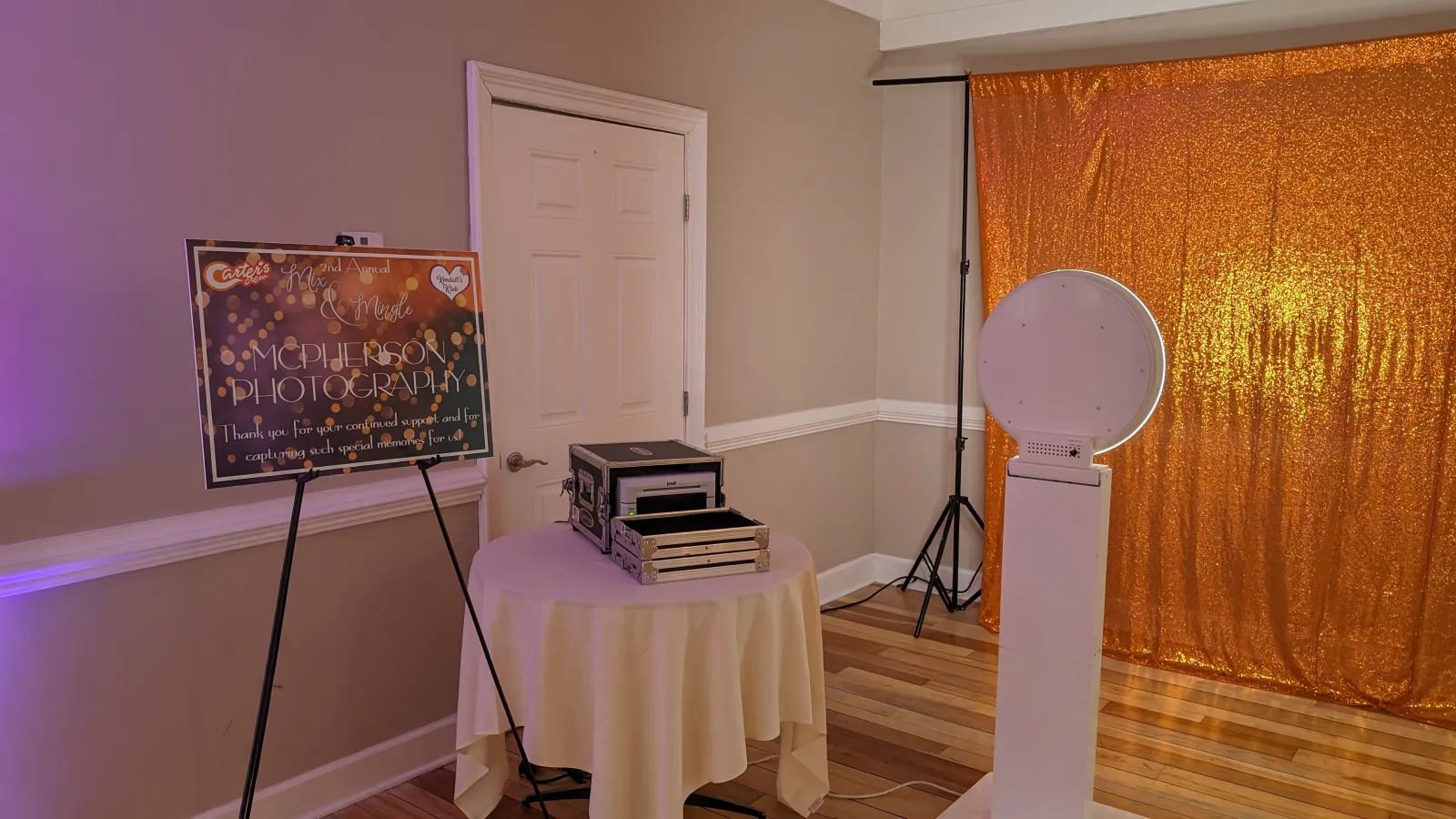Photo booth with gold sequin backdrop and on-site photo printer at a charity event