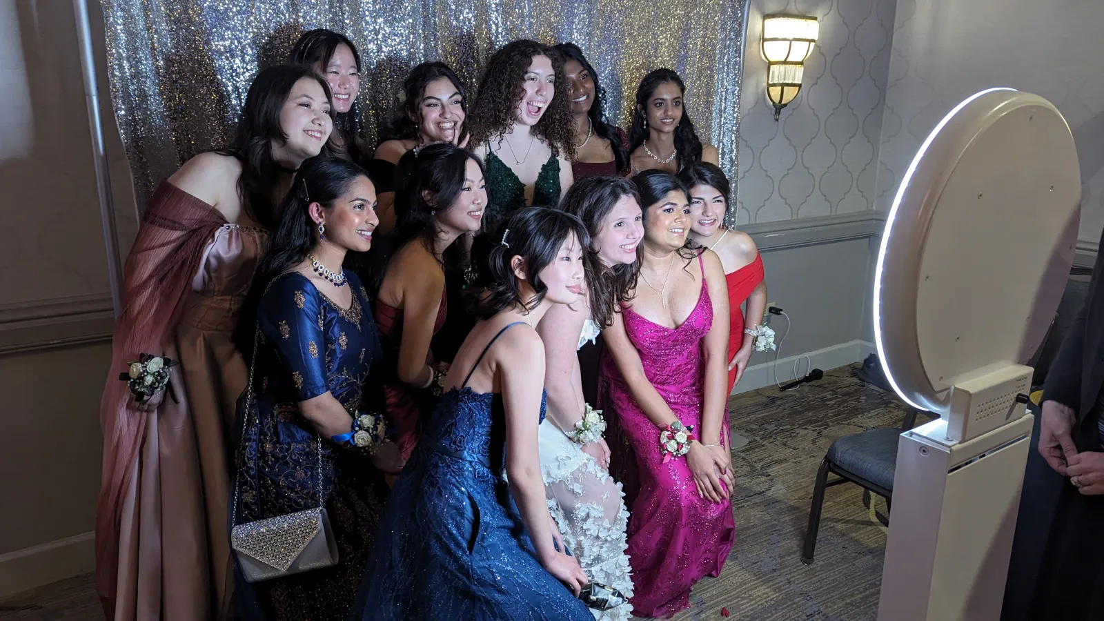 Prom guests posing at the NWN Entertainment social photo booth in front of a silver sequin backdrop