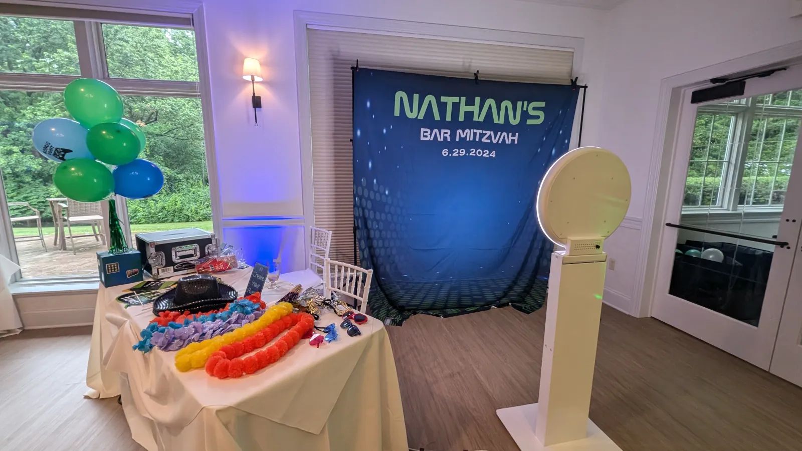 Photo booth setup with a custom Bar Mitzvah backdrop and a table of props