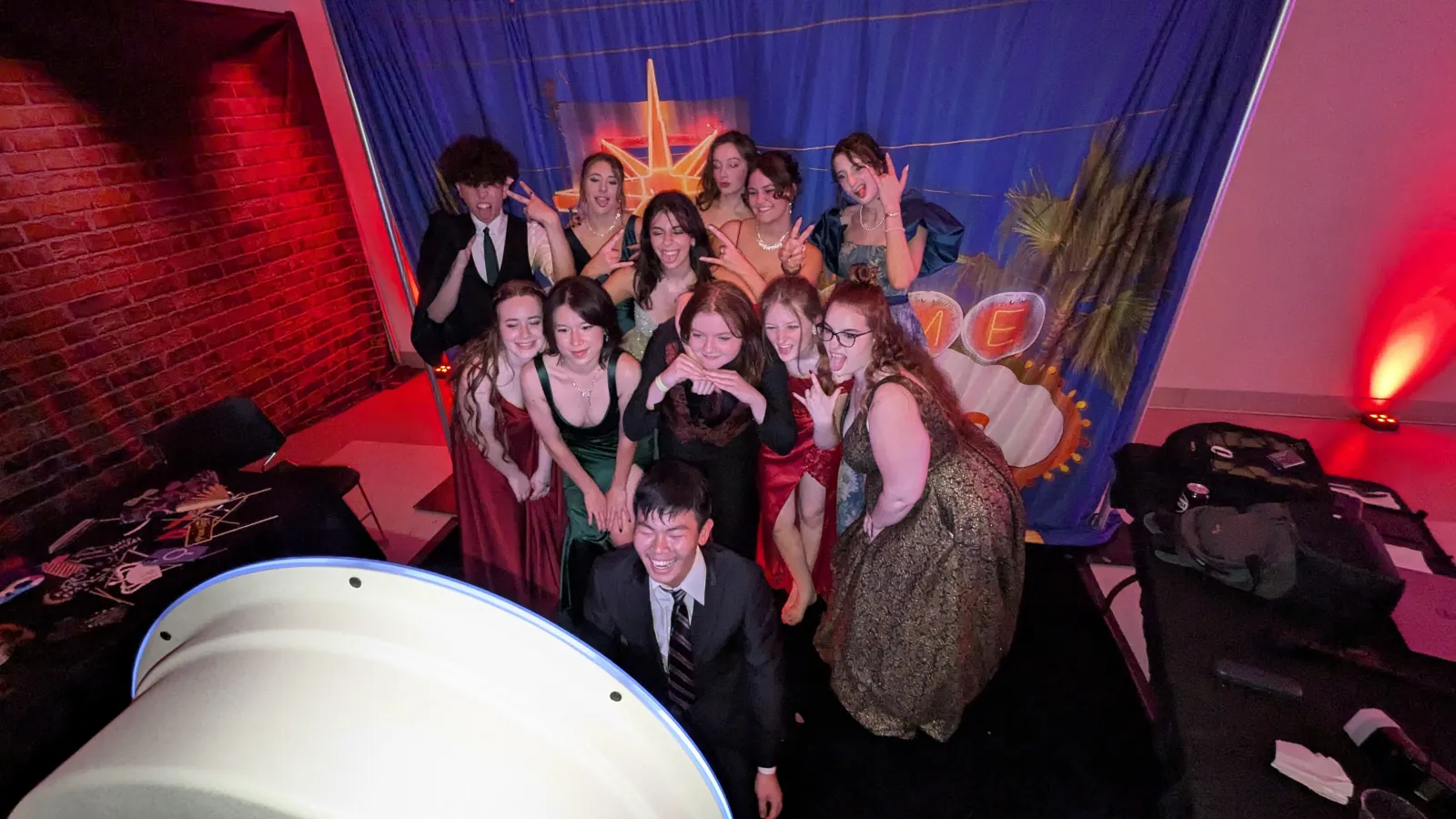 Students making faces at the NWN photo booth during a prom with a Vegas-themed backdrop